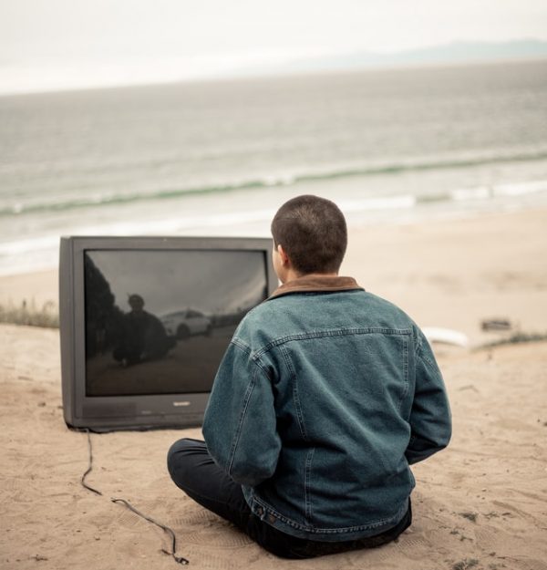 Man watching a blank TV screen alone at the beach